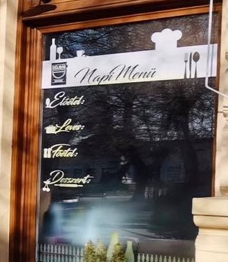 A Napi Menü feliratú tábla a kávézó kirakatában, előétel, leves, főétel és desszert sorokkal