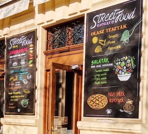 A kávézó két street food krétatáblája a homlokzaton, hamburgerek, olasz tészták és saláták rovatokkal