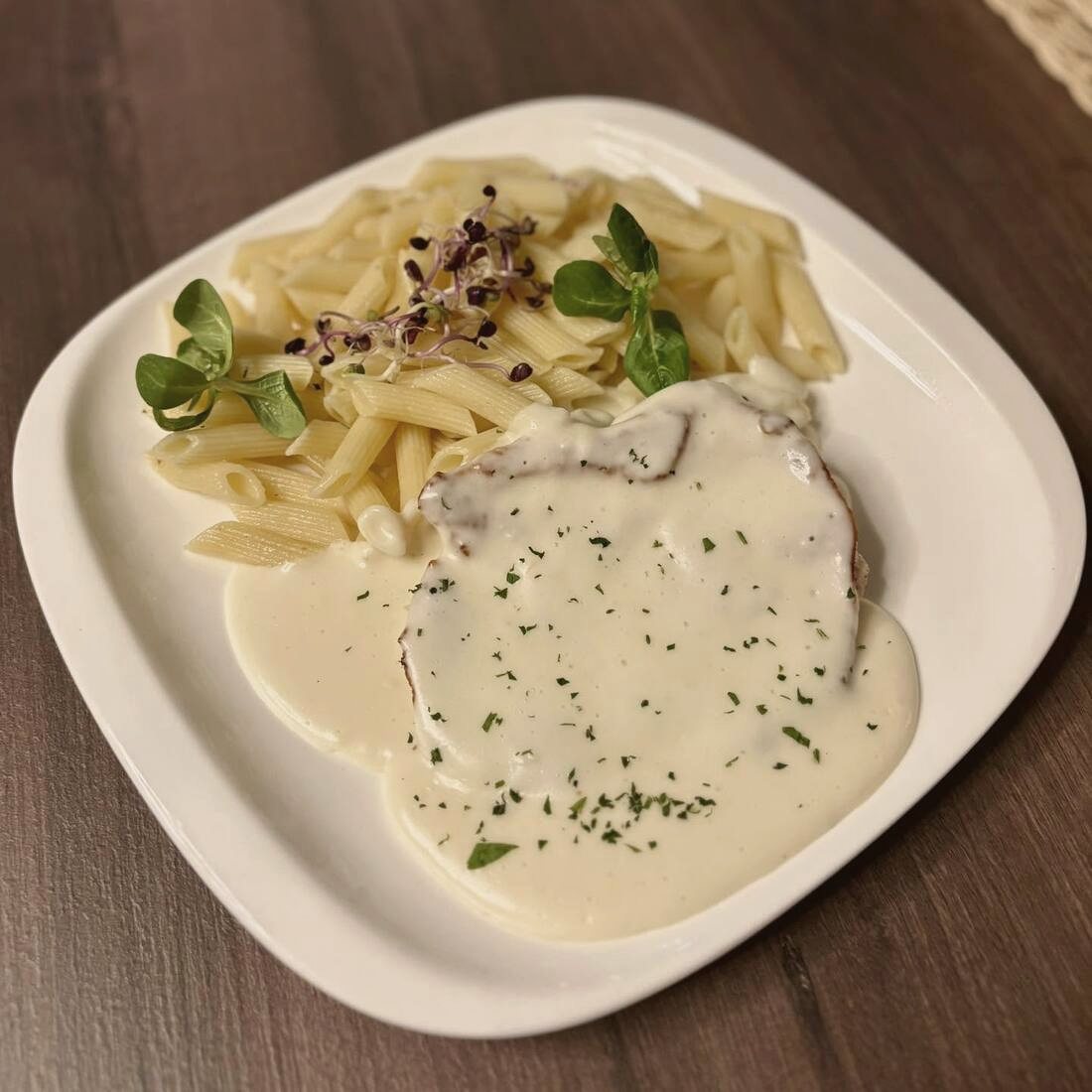 Penne tejszínes mártásban, hússzelettel, fehér tányéron