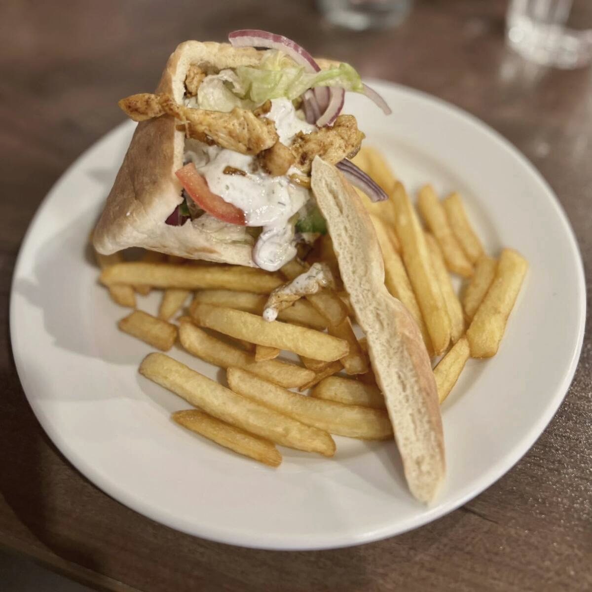 Csirke gyros pitába töltve, tányéron burgonyával