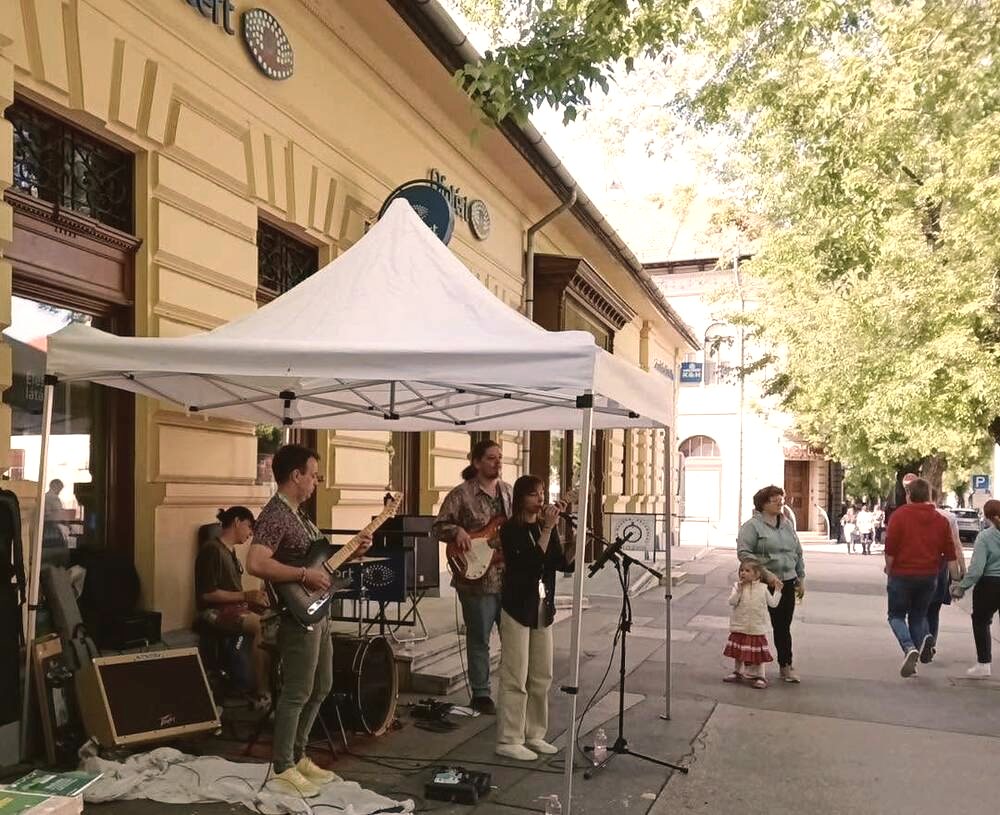 Utcazene a Szabadság téren, háttérben a kávézónak otthont adó sárga műemlék-épület